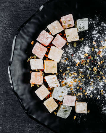 Top view turkish delight lokums in plate on black textured background. verticalの写真素材