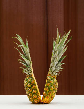 Pineapple cut in half side view on a wooden wall and white backgroundの写真素材