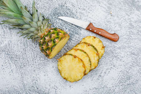 Sliced pineapple with a fruit knife on grunge background, flat lay.の写真素材