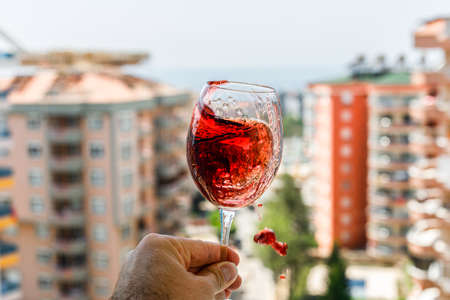 Splashing red wine with ice in a glass side view on buildings along the way backgroundの写真素材