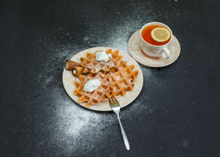 Some waffles with tea in a plate on dark background, high angle view.の写真素材