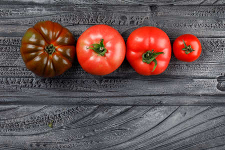 Colorful tomatoes top view on a grey wooden background