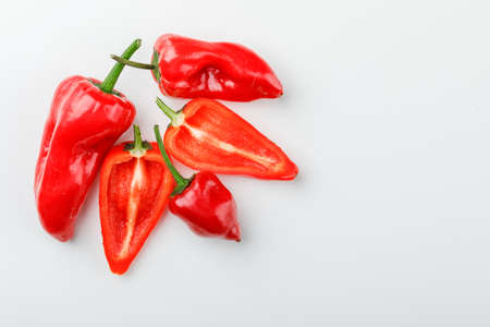 Red peppers with slices on white background, flat lay.