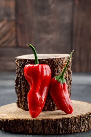 Red peppers with wooden pieces side view on grey and stone tile backgroundの写真素材
