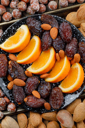 Orange slices with dates, almonds and nuts in a plate on copper tray background, high angle view. の写真素材