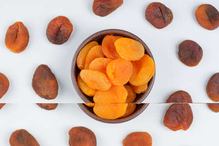 Dried apricots in a clay bowl on a white background. top view.