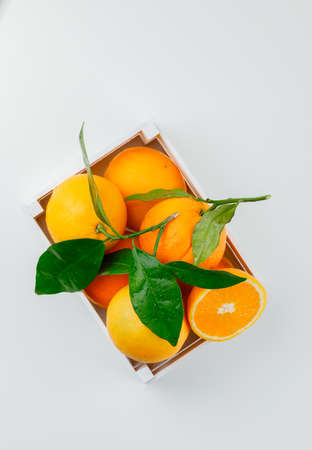 Delicious oranges in a wooden box with branch top view on a white background の写真素材