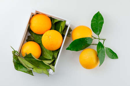 Oranges and leaves in a wooden box on a white background. top view.の写真素材