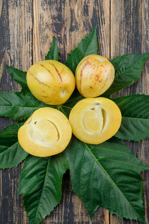 Greenish exotic fruit top view on wooden and leaves background