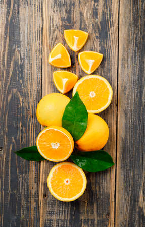 Sliced oranges with leaves flat lay on old wooden background