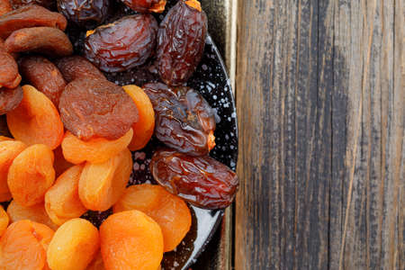 Dried apricots with dates in a plate on wooden background, close-up.の写真素材