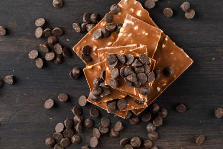 Choco drops with choco bars top view on a wooden background 
