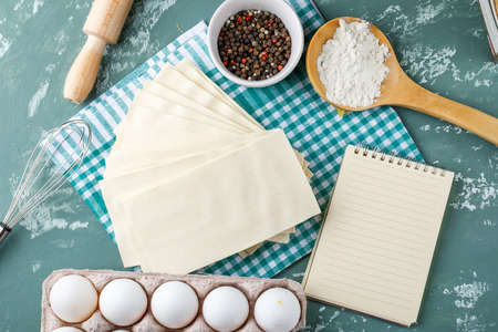 Napkins with eggs, peppercorns, starch, whisk, rolling pin, copybook on grunge and kitchen towel background, flat lay.の写真素材