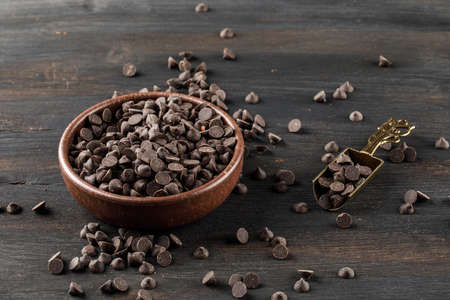 Choco drops in a bowl with scoop high angle view on a wooden background 
