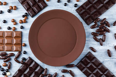 Chocolate bars with candies, plate on grungy background, top view.の写真素材