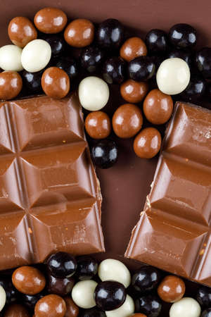 Chocolate bars with chocoballs top view on a brown background