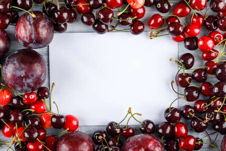 Cherries and plums with empty paper flat lay on a grunge backgroundの写真素材