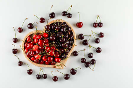 Sweet cherries in a wooden plate on white background, top view.の写真素材