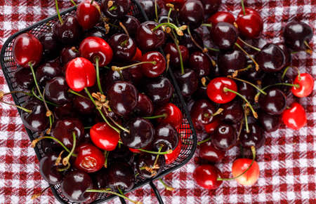 Cherries in a cullender on a picnic cloth background. flat lay.の写真素材