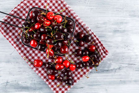 Cherries in a cullender on grunge and picnic cloth background. flat lay.の写真素材