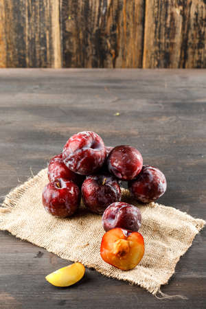 Red plums with piece of sack high angle view on wooden and grungy backgroundの写真素材