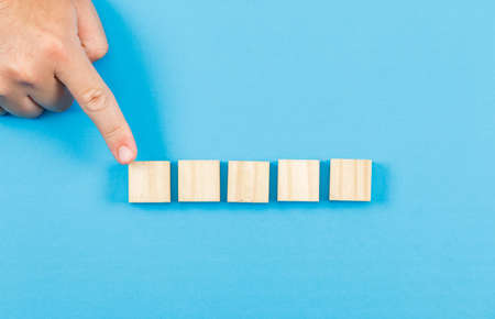 Business and financial concept on blue backgroud flat lay. businessman showing wooden block.