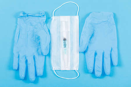 Medical gloves with face mask, injection on blue background, flat lay.の写真素材