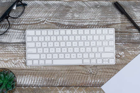 Top view keyboard with eyeglasses, paper, pen, cactus on wooden background. horizontal