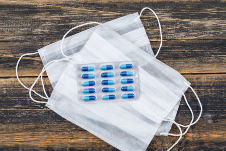 Capsules with face masks in a blister pack on wooden background, flat lay.の写真素材
