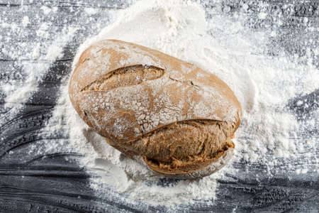 Bread top view on a floury dark wooden background 
