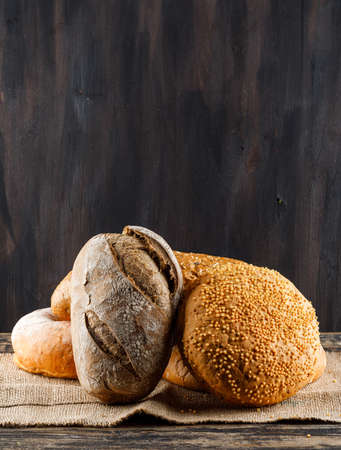 Side view bread with bakery products on wooden background. vertical free space for your textの写真素材