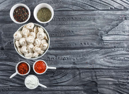 Top view dough in bowl with sauce, spices on gray wooden background. horizontal space for textの写真素材