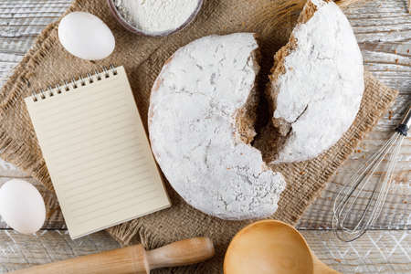 Top view cake with notepad, eggs, rolling pin on sack cloth and wooden background. horizontalの写真素材