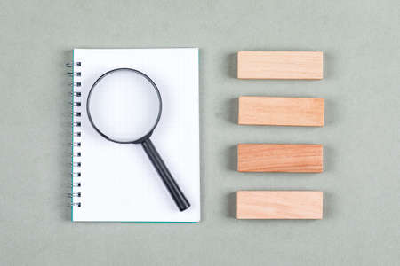 Searching and research concept with notebook, magnifier, wooden blocks on gray background top view. horizontal imageの写真素材