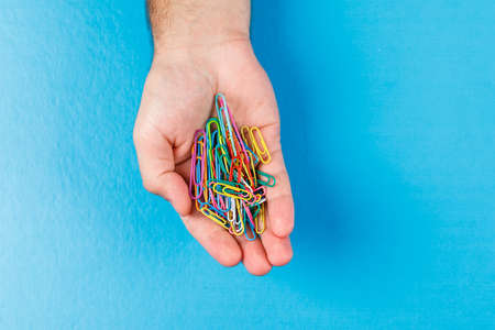 Business and financial concept with paper clips on the palm on blue background flat lay.の写真素材