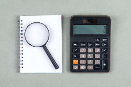 Time management and research concept with notebook, magnifier, calculator on gray background top view. horizontal image の写真素材