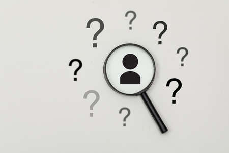 Business and searching concept with magnifying glass, question marks, human head silhouette on grey...