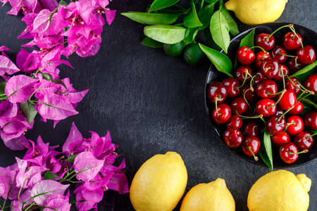 Lemons with leaves, flowers, cherries on grey background, flat lay.の写真素材