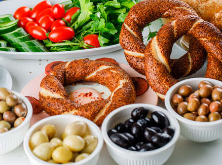 Eggs with sausage in a plate with a cup of tea, turkish bagel, salad high angle view on a white...