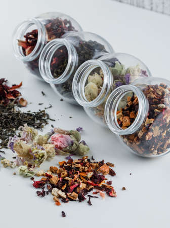 Assorted dried herbs in plastic jars high angle view on white and grunge backgroundの写真素材