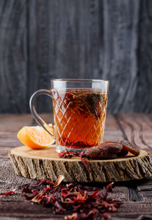 Tea with dried fruits and flowers, lemon on wood in a cup on stone tile and wooden background, side view.の写真素材