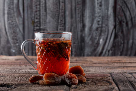 Tea with dried fruits in a cup on stone tile and wooden background, side view.の写真素材