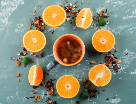 Tea with mixed dried herbs, oranges, limes in a cup on plaster background, flat lay.の写真素材
