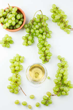 Green grapes in a plate with wine in goblet top view on a white backgroundの写真素材