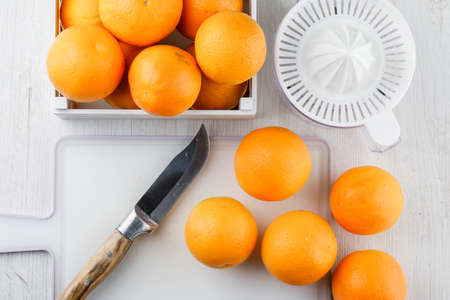 Oranges with squeezer, knife, cutting board in a wooden box on wooden background, top view.の写真素材