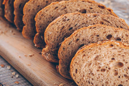 Sliced bread on a cutting board on a wooden table and gray background. side view. 