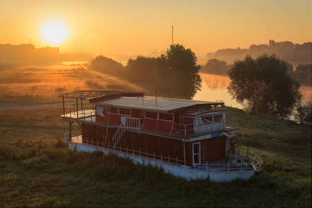 An old boat at sunrise by the river Sava under the Bridge of Liberty in Zagreb, Croatia, Europeの写真素材