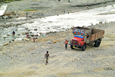 Assam, India - September 30th, 2007: Unidentified road workers and people on river bed by morning toilet in the small river on the border to Bhutanのeditorial素材