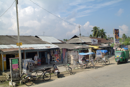 Assam, India - September 30th, 2007: Unidentified people and poor looking shops on a road in a small...