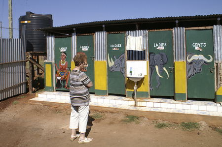Amboseli Nationalpark, Kenya - January 30th 2011: unidentified woman in front of colorful painted toilets in a lodge in Amboseli Nationalparkのeditorial素材
